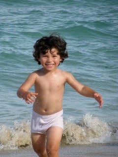 A young boy is running in the water.