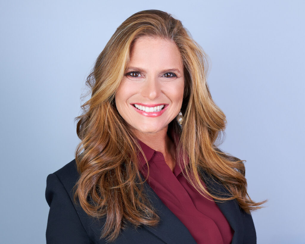 Professional woman with long wavy hair smiles confidently.