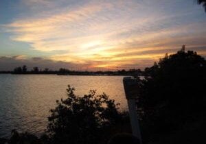 A sunset over the water with trees in front of it.